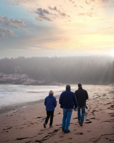 Family Strolling Along Misty Beach at Sunset