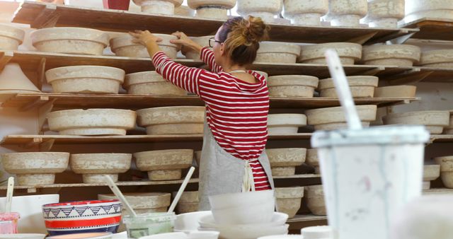 Woman in Pottery Studio Rearranging Ceramic Pieces on Shelves - Download Free Stock Images Pikwizard.com