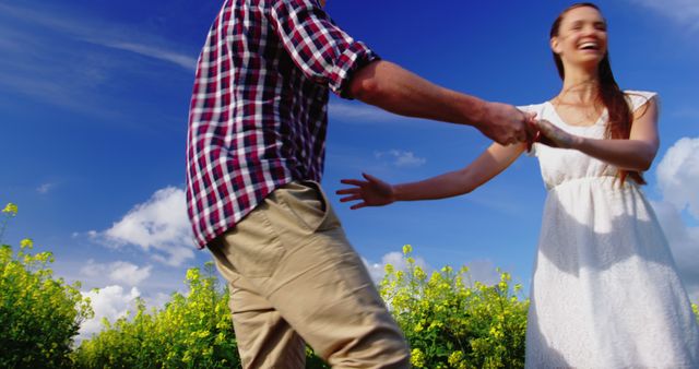 A joyful Caucasian couple spins hand-in-hand in a field, embodying outdoor bliss. - Download Free Stock Photos Pikwizard.com