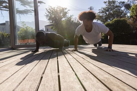 Diverse Friends Exercising Together Performing Push-Ups Outdoors