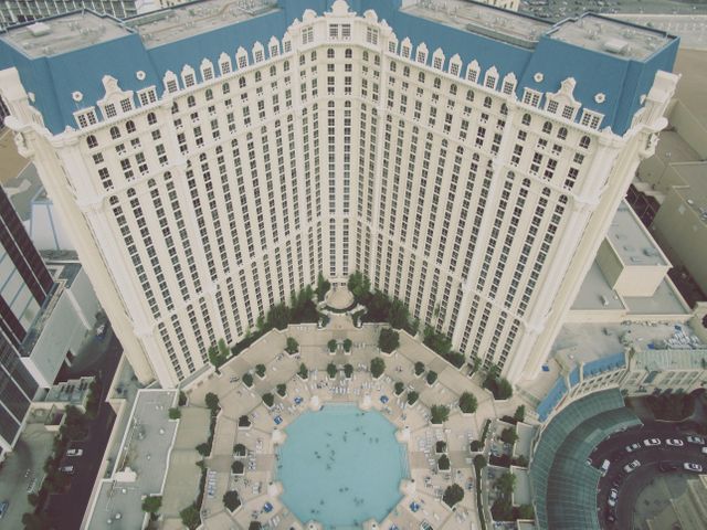 This aerial view showcases a luxurious high-rise resort with an expansive pool area. Ideal for use in travel and tourism campaigns, hotel advertisements, brochures, and urban design presentations. Highlights the grandeur and attractiveness of the resort, appealing to vacation travel seekers and design professionals.