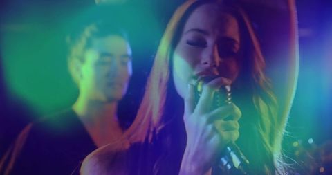 Female Lead Vocalist Singing with Retro Microphone under Neon Haze on Stage