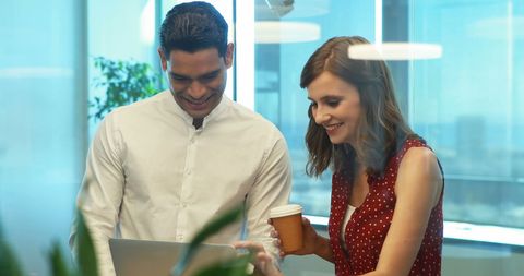 Colleagues Collaborating Over Laptop in Bright Office Setting