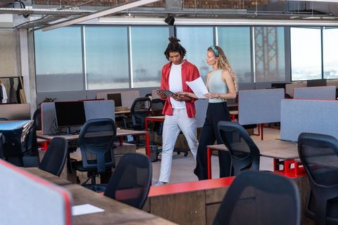 Diverse Coworkers Discussing Work in Modern Open-Plan Office