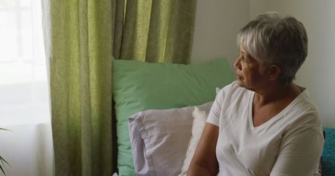 Senior Woman Reflecting Alone in Bright Bedroom