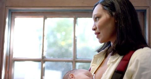 Asian mother nursing infant by window