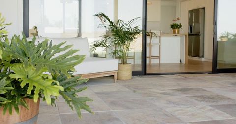 Minimalist patio featuring lush potted foliage, tiled floor, sliding glass doors