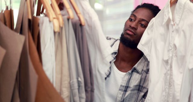 Man Browsing Clothes in Store with Focused Expression - Download Free Stock Images Pikwizard.com