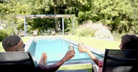 Couple Enjoying Relaxing Summer Day by Swimming Pool with Refreshing Drinks