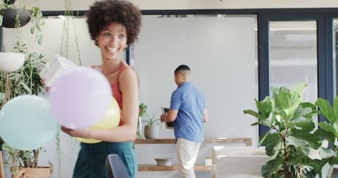 Businesswoman enjoying lunch break with balloons in creative office