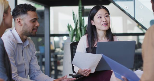 Young professionals discussing project while sitting in a modern office. Ideal for illustrating teamwork, office dynamics, business strategy sessions, meetings, and collaboration in professional settings.