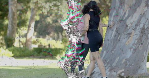 Walking friends embracing near large tree in sunny park with colorful digital glitch overlay