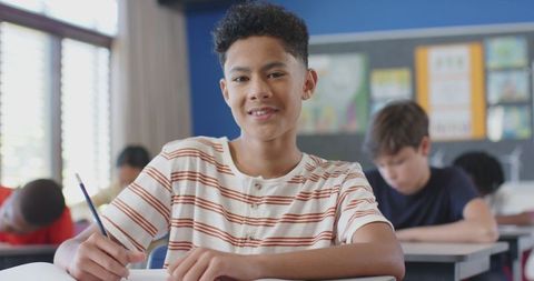 Confident Student Writing in Classroom Surrounded by Peers - Download Free Stock Images Pikwizard.com