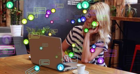 Freelancer taking call while working on laptop in cafe with social chat bubbles overlay