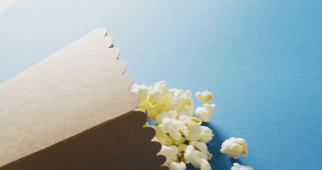 Close-up of Popcorn Box with Popcorn Scattered on Blue Background - Download Free Stock Images Pikwizard.com