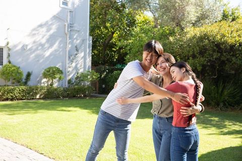Asian family embracing outdoors on sunny summer day