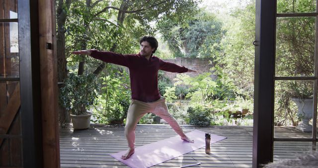 Man engaging in yoga on serene wooden deck surrounded by lush greenery, ideal for promoting wellness and relaxation themes. Suitable for use in blogs, wellness centers, exercise programs, and meditation apps.