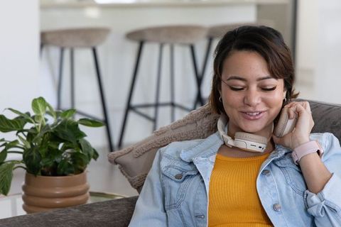 African american woman lounging on couch listening to music with wireless headphones