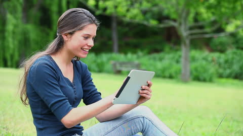 Joyful Young Woman Using Tablet in Lush Green Park