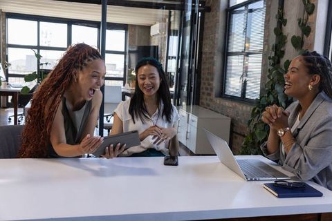 Diverse Female Professionals Sharing Laughter at Office Table
