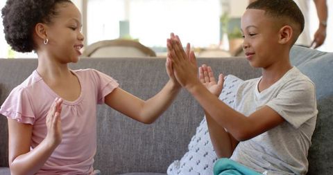 Playful Siblings Enjoying Fun Clapping Game on Sofa