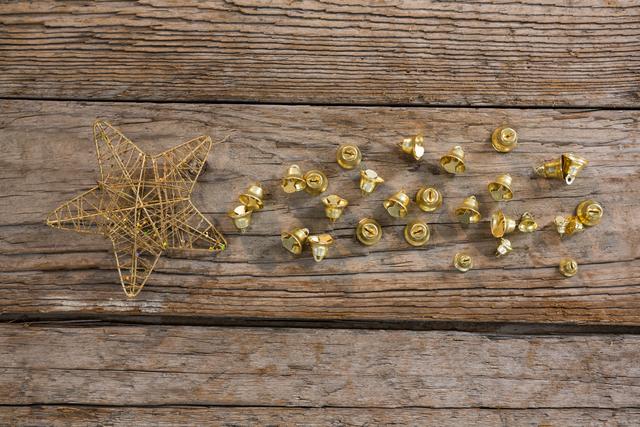 Golden Christmas bells and a star arranged on a rustic wooden plank, perfect for holiday-themed designs, festive invitations, seasonal greeting cards, and Christmas decoration ideas.