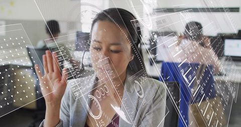 Mid-adult woman interacting with holographic data interface in modern open office