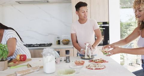 Diverse Friends Enjoy Making Homemade Pizza in Modern Kitchen