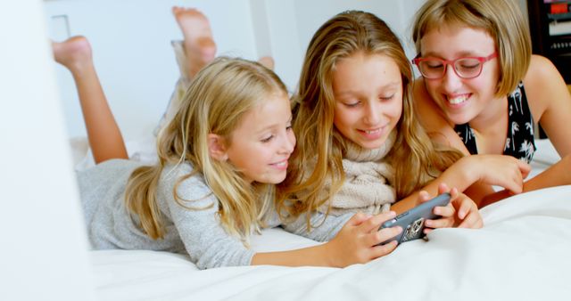 Three Girls Lying on Bed and Smiling While Playing with Smartphone - Download Free Stock Images Pikwizard.com