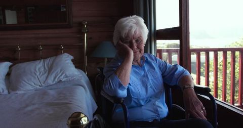 Thoughtful Elderly Woman in Wheelchair by Bedroom Window