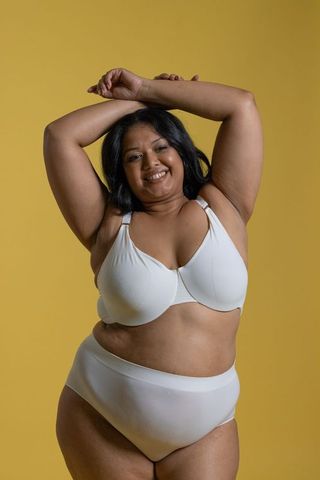 Smiling plus-size asian woman posing in white lingerie, embracing body positivity