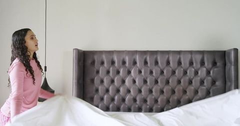Woman making bed with comfortable tufted headboard design