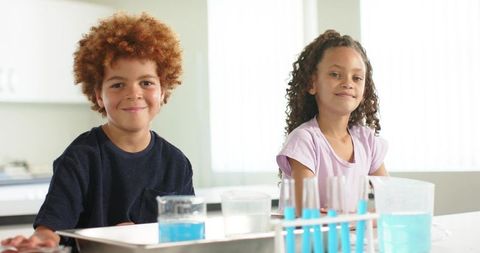 African american children conducting bright science experiment with blue liquids in classroom