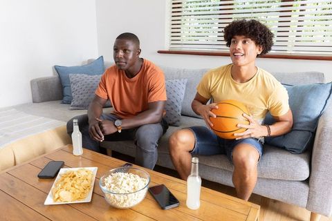 Diverse Friends Watching Sports at Home Enjoying Snacks
