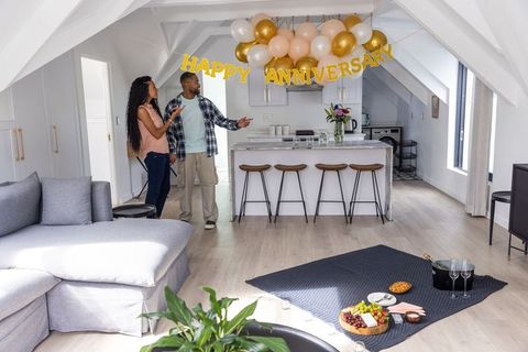 Couple celebrating anniversary in bright loft kitchen with balloons and picnic spread