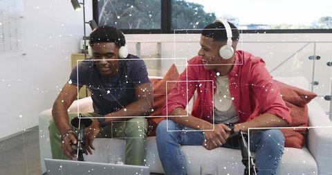 Recording podcast on sofa with headphones and microphones, laptop streaming and collaboration