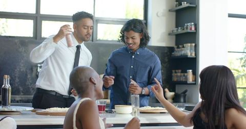 African american friends seasoning and preparing pizza at sunlit modern kitchen island