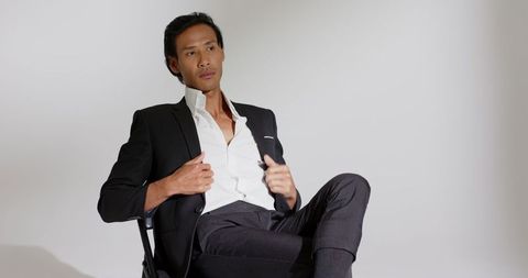 Confident male model in stylish black suit in minimalistic studio
