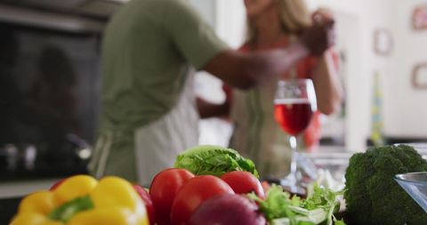 Couple Dancing in Kitchen While Cooking with Fresh Vegetables