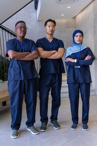 Diverse medical team in navy scrubs standing with arms crossed in hospital lobby