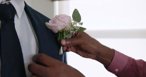 Attaching a boutonniere to a suit jacket at a wedding