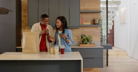 Couple Connecting Over Groceries and Technology in Modern Kitchen