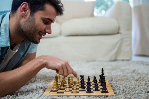 Man contemplating move on chessboard in relaxing home environment