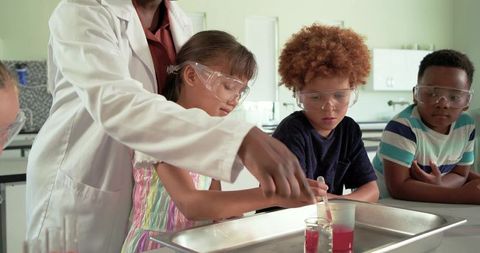 African american teacher guiding elementary students doing hands-on science experiment