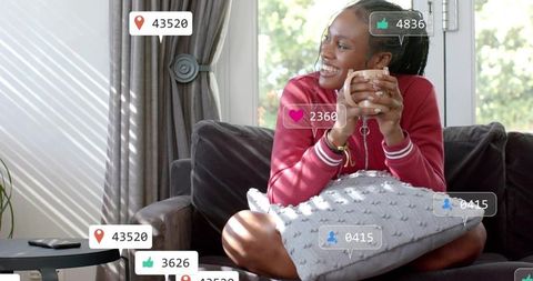 Woman Relaxing on Sofa with Mug and Smartphone at Home