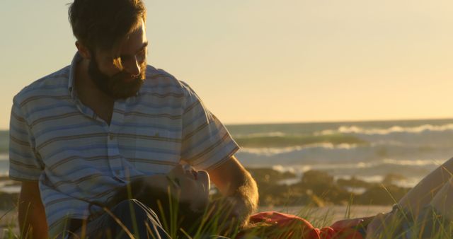Young man caressing womans hair while lying on mans lap. Couple romancing on beach during sunset 4k