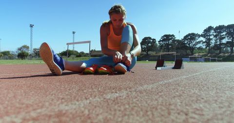 Female Athlete Tying Shoe on Track during Sunny Day - Download Free Stock Images Pikwizard.com
