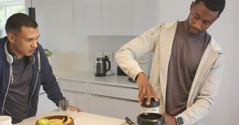 Two friends grinding coffee on white counter, morning routine with headphones and smartwatch