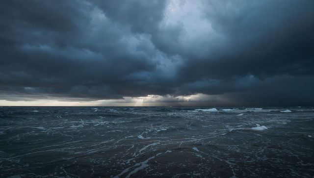Dramatic Storm Clouds Over Roaring Ocean with Sun Rays