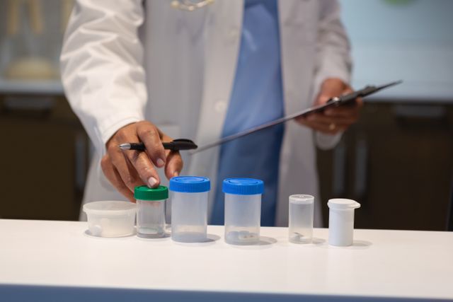 Doctor organizing various medical containers on a counter in a hospital. Ideal for use in healthcare, medical research, and hospital-related content. Can be used in articles, presentations, and educational materials about medical procedures and healthcare professionals.